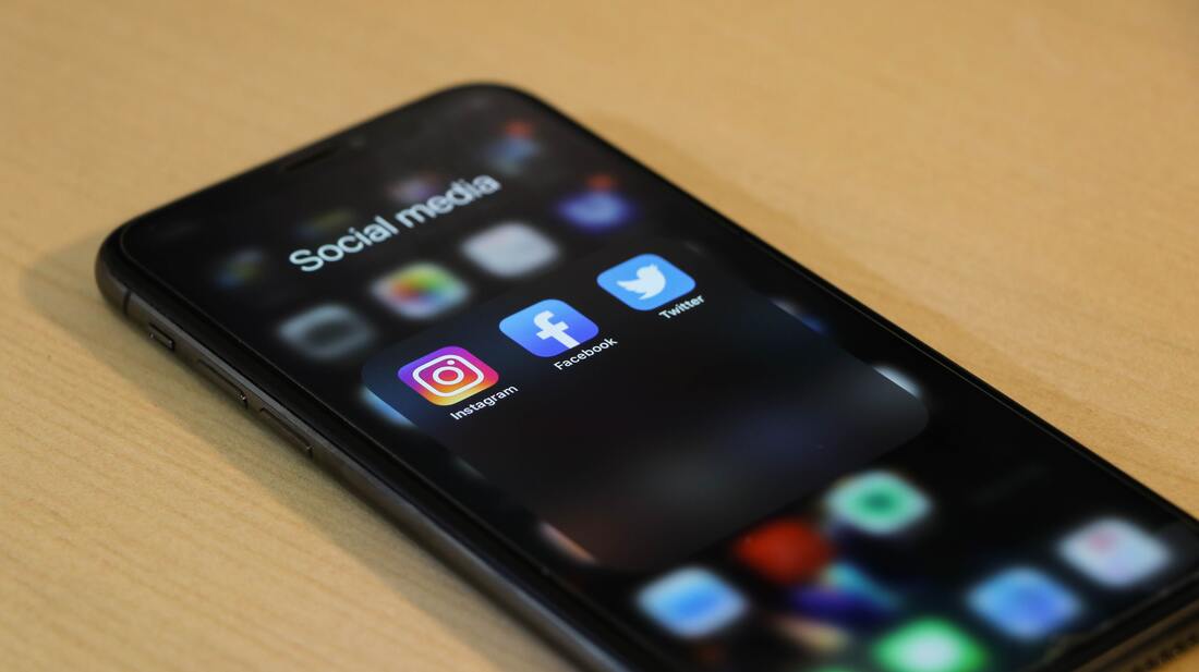 iPhone with social media folder showing Instagram, Facebook, and Twitter apps